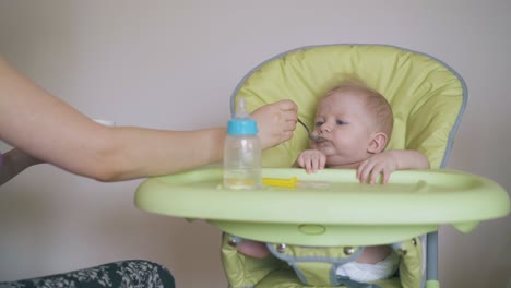 mommy-feeds-little-son-with-wholesome-meal-in-highchair