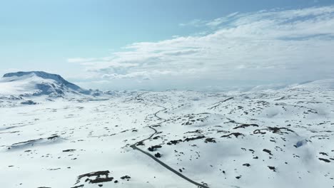 Stunning-view-of-road-55-crossing-Sognefjellet-mountain-pass-between-Luster-and-Lom-in-Norway---Springtime-sunny-aerial-with-snow-left-in-landscape