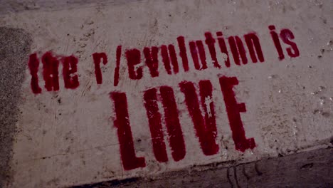 Close-up-of-Berlin-wall-with-revolution-is-love-graffiti,-rack-focus,-night