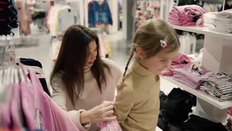 Mutter-Mit-Tochter-Im-Einkaufszentrum-Probiert-Rosa-Jacke-Aus