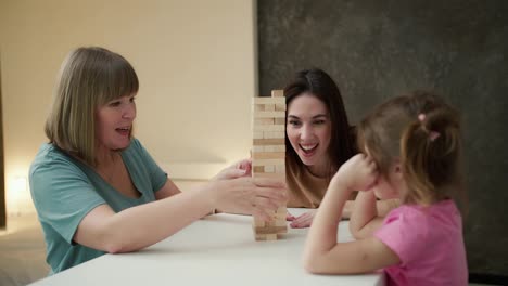 Glückliches-Kleines-Mädchen-Mit-Mutter-Und-Großmutter,-Die-Drinnen-Zu-Hause-Jengo-Spielen
