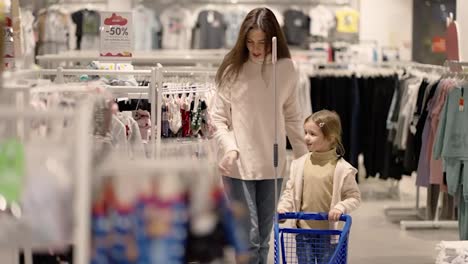 Mother-and-daughter-walking-through-a-clothing-store-with-children-shopping-cart