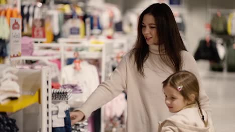 Mother-and-daughter-walking-through-a-clothing-store-with-girl-in-a-shopping-cart