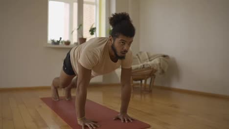 Young-man-performing-legs-stretch-exercise-at-home