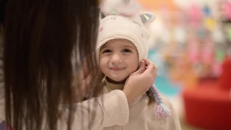 Mother-and-daughter-try-on-cute-cartoon-hat-in-the-shopping-mall