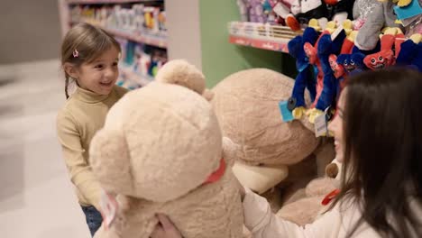 Mother-gives-big-soft-bear-toy-to-her-daughter-in-children's-department-store