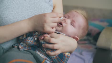 woman-gives-nasal-drops-to-little-son-in-light-room-closeup