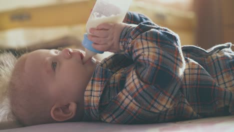 Kleines-Baby-Isst-Leckere-Milchmischung-Aus-Einer-Kleinen-Flasche-Auf-Dem-Bett