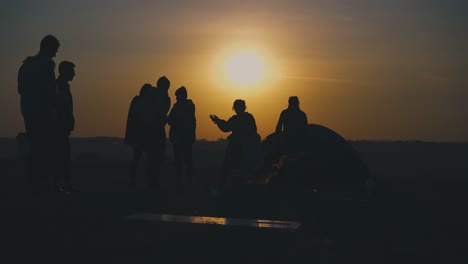 Junge-Touristen-Ruhen-Sich-Bei-Sonnenuntergang-Am-Brennenden-Lagerfeuer-Aus