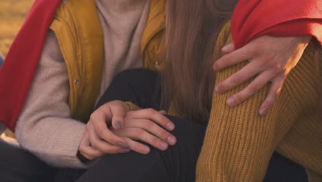 guy-and-girl-join-hands-sitting-at-bonfire-in-camp-closeup