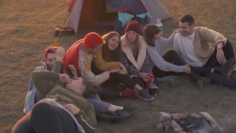 positive-tourists-rest-at-burning-bonfire-in-camp-in-evening