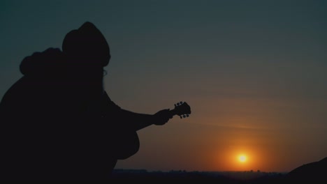silhouettes-of-man-playing-guitar-and-people-resting-at-camp