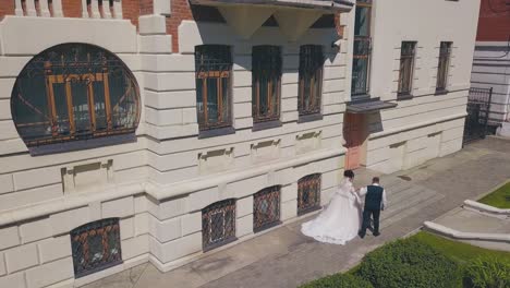 Braut-Und-Bräutigam-Gehen-Zu-Schönen-Gebäudestufen,-Luftaufnahme