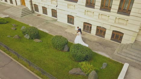 Braut-Und-Bräutigam-Gehen-Entlang-Des-Rasens-In-Der-Nähe-Des-Gebäudes-Von-Oben