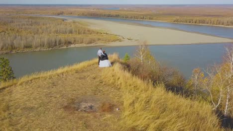 just-married-couple-enjoys-river-view-from-hill-aerial-view
