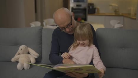 Old-grandfather-is-reading-book-to-his-granddaughter