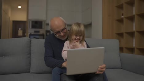 Grandfather-and-small-granddaughter-having-video-call-together-using-laptop