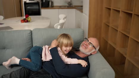 The-granddaughter-jump-on-her-grandfather-on-the-sofa-and-hug-him