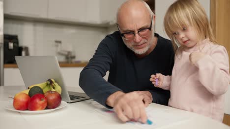 Grandfather-teach-granddaughter-drawing-and-doing-homework-at-home