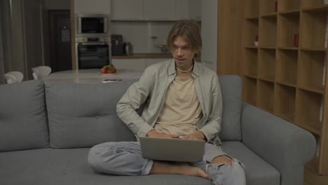 Hombre-Relajado-Sentado-En-Un-Sofá-Trabajando-Desde-Casa-En-Una-Computadora-Portátil