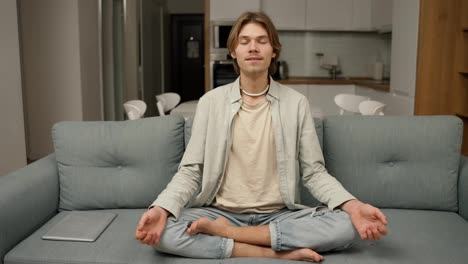 Der-Junge-Mann-Beginnt-In-Seinem-Wohnzimmer-Auf-Der-Couch-Zu-Meditieren