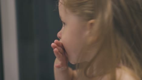 little-girl-washes-mouth-with-water-at-mirror-in-bathroom