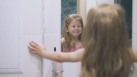 Kleines-Mädchen-Mit-Blauen-Augen-Blickt-Im-Hellen-Badezimmer-In-Den-Spiegel