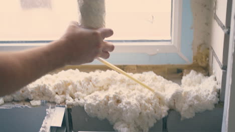 constructor-applies-spray-foam-insulation-in-room-close-view