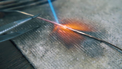 heating-of-gold-rod-with-flame-on-asbestos-table-closeup