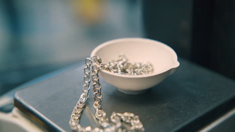jeweler-puts-white-gold-chain-into-bowl-on-scale-closeup