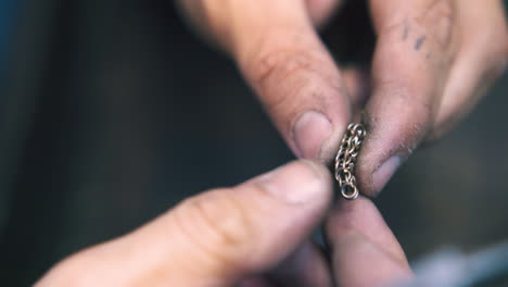 jeweler-connects-link-and-looks-at-chain-in-workshop-closeup