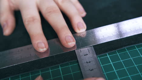Professional-tailor-measures-leather-with-rulers-closeup
