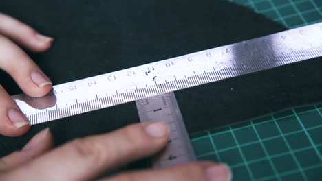 Tailor-moves-metal-rulers-measuring-black-leather-cloth