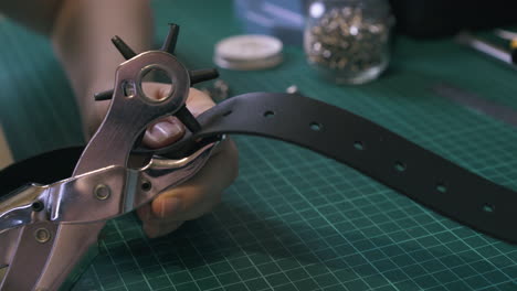 Professional-tailor-makes-holes-in-belt-with-punch-pliers