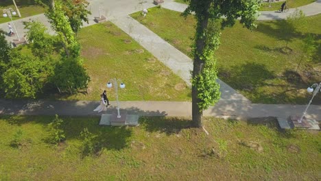 just-married-couple-walks-along-green-park-aerial-view