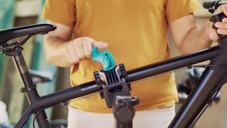 Man-clamps-bicycle-body-on-repair-stand