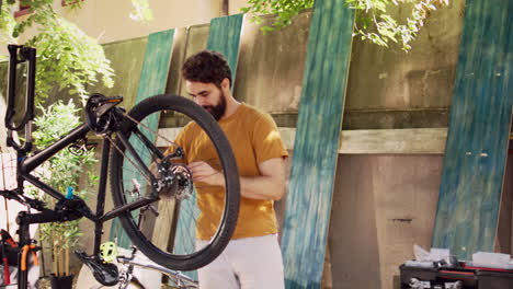 Male-cyclist-mending-bike-wheel-in-yard