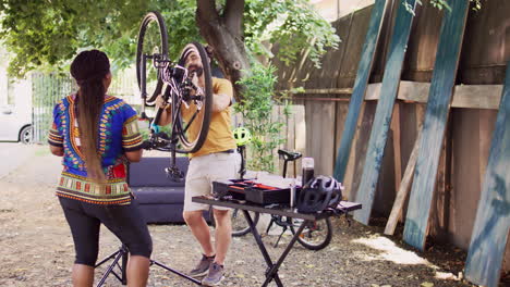 Couple-servicing-modern-bicycle-in-yard