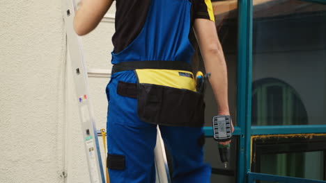 Technician-holds-drill-climbing-ladder