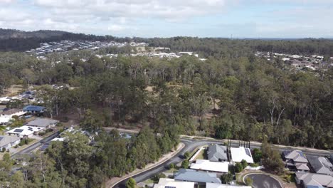 Aerial-view-of-a-residential-estate-in-Australia,-drone-flying-over-homes-towards-bushland-and-a-green-field