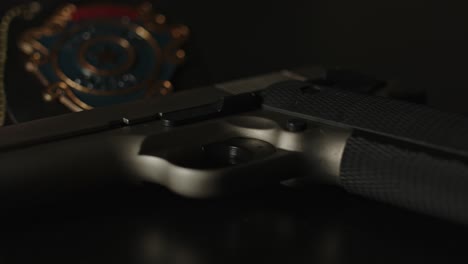 Filmischer-Schwenk-über-Die-Pistole-Mit-Einem-Polizeiabzeichen-Im-Hintergrund