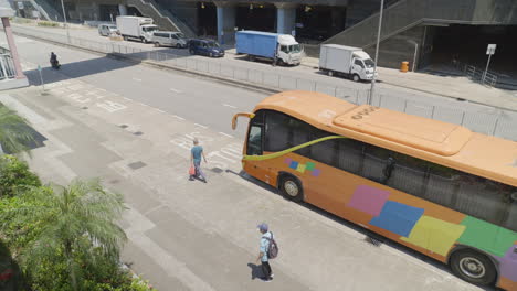 Nach-Vorne-Schwenkende-Aufnahme-Von-Oben-Oder-Menschen,-Die-Neben-Einem-Bus-Auf-Einer-Ruhigen-Straße-In-Hongkong,-Asien,-Laufen