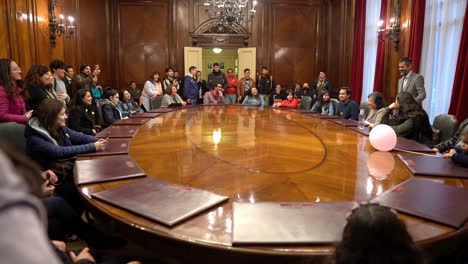 Tilt-up-of-the-main-boardroom-of-the-Central-Bank-of-Chile-filled-with-visitors,-giant-oval-table,-Santiago-Chile