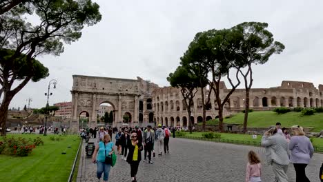 Turistas-Haciendo-Turismo-De-Un-Día-Con-El-Arco-De-Constantino-Y-El-Famoso-Coliseo-En-El-Fondo,-Roma,-Italia