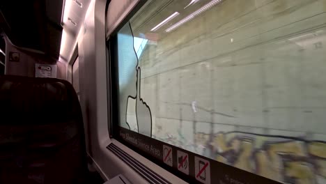 A-view-looking-out-of-the-window-of-a-train-travelling-on-the-outskirts-of-a-city-in-an-empty-Frecciarossa-Business-Class-carriage,-Italy
