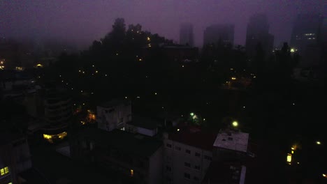 Aerial-view-dolly-in-establishing-night-view-of-Lastarria-neighborhood-and-Santa-Lucia-hill,-desolate-and-gloomy-perspective,-cloudy-morning