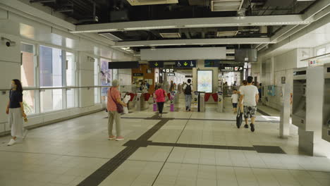 Toma-Panorámica-Hacia-Adelante-Moviéndose-Hacia-La-Entrada-De-La-Estación-De-Metro-De-Hong-Kong-Con-Gente-Caminando-Y-Viviendo-La-Vida-Cotidiana.