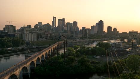Luftbild-Hyperlapse-Bei-Sonnenuntergang-über-Der-Insel-Hennepin-Entlang-Der-Steinbogenbrücke,-Verheerender-Dunst-über-Der-Skyline-Der-Stadt-Minneapolis,-Minnesota,-USA