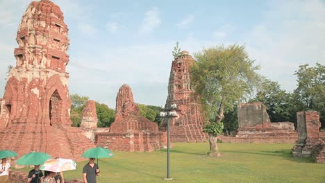 Tourists-Walking-Along-Wat-Maha-That-Thai-Temple-Ruins-in-Ayutthaya-on-a-Hot-Day-with-Umbrellas