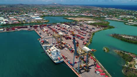 Shipping-container-port-docked-at-cranes,-Curacao-Caribbean-island,-aerial-pullback